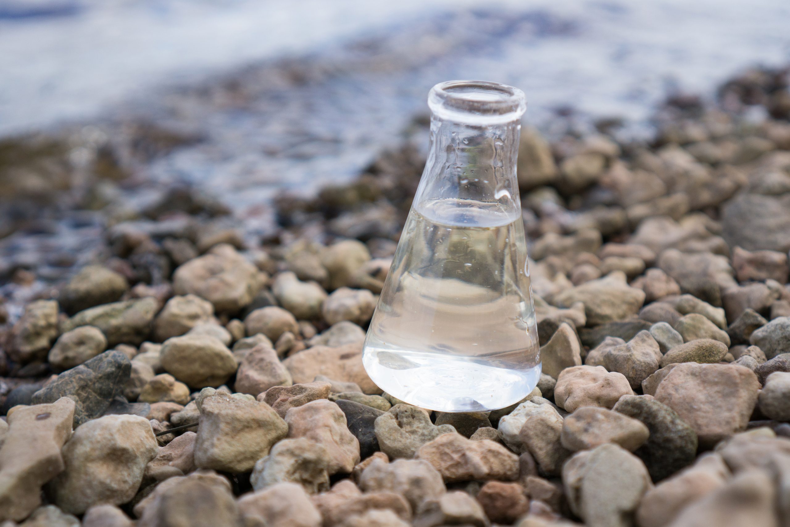 Chemical flask with water, lake or river in the background